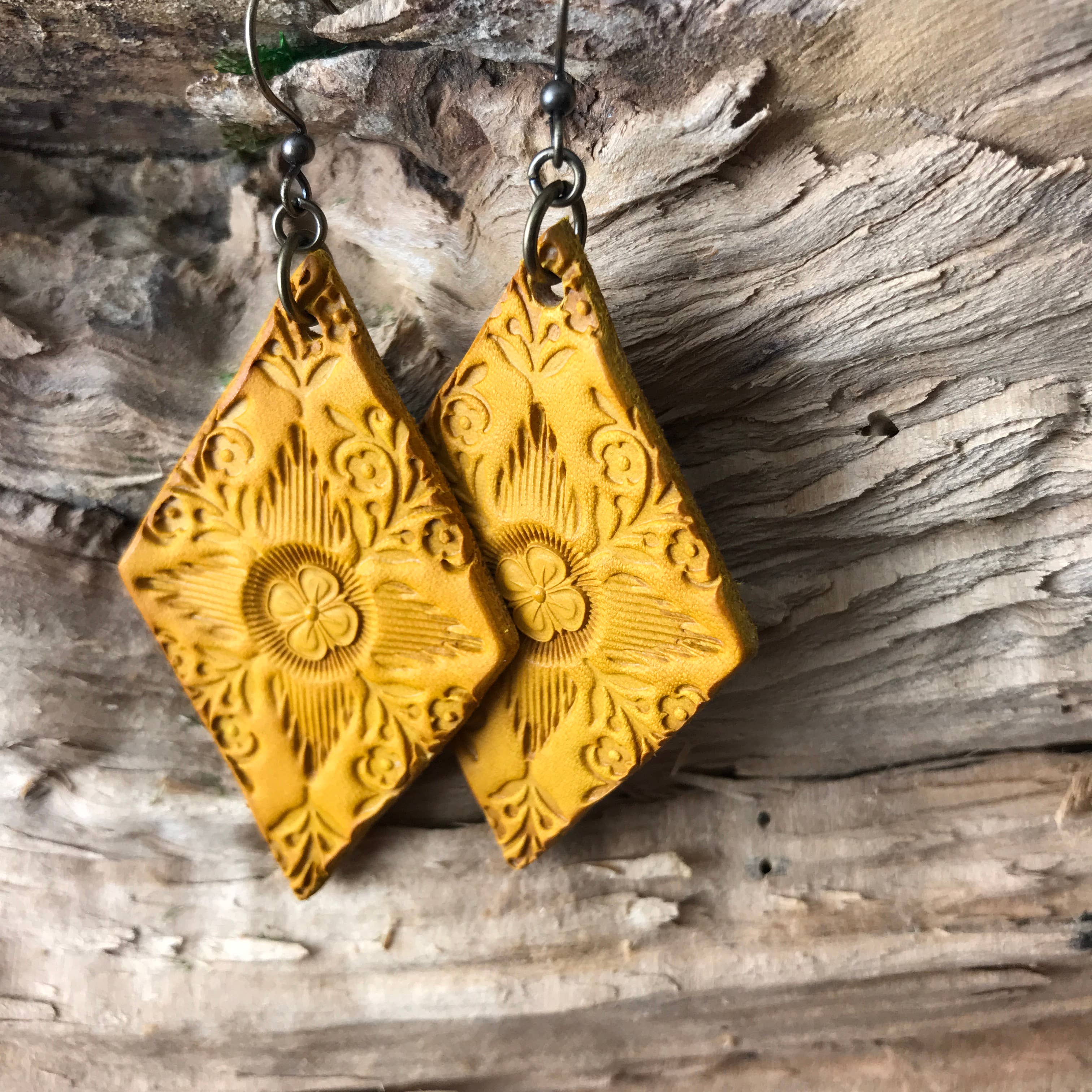 Artisan handcrafted yellow leather textured earrings on a wooden surface