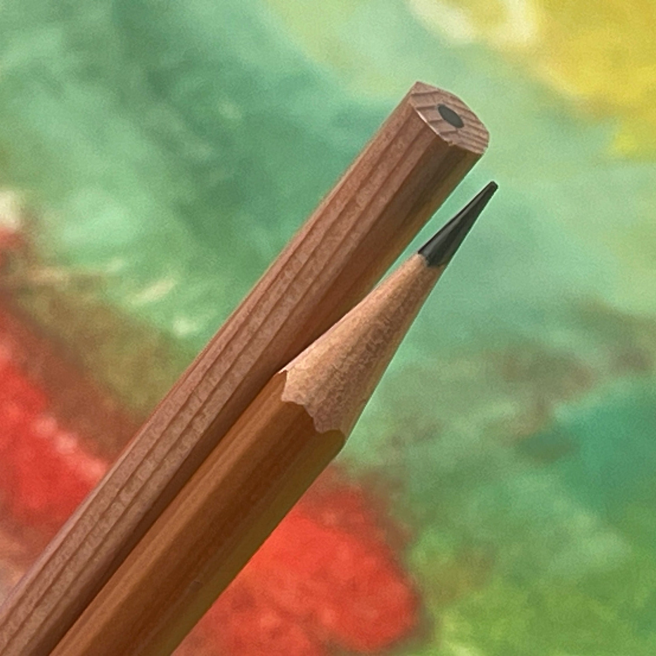 Two pencils with one sharpened against a colorful background