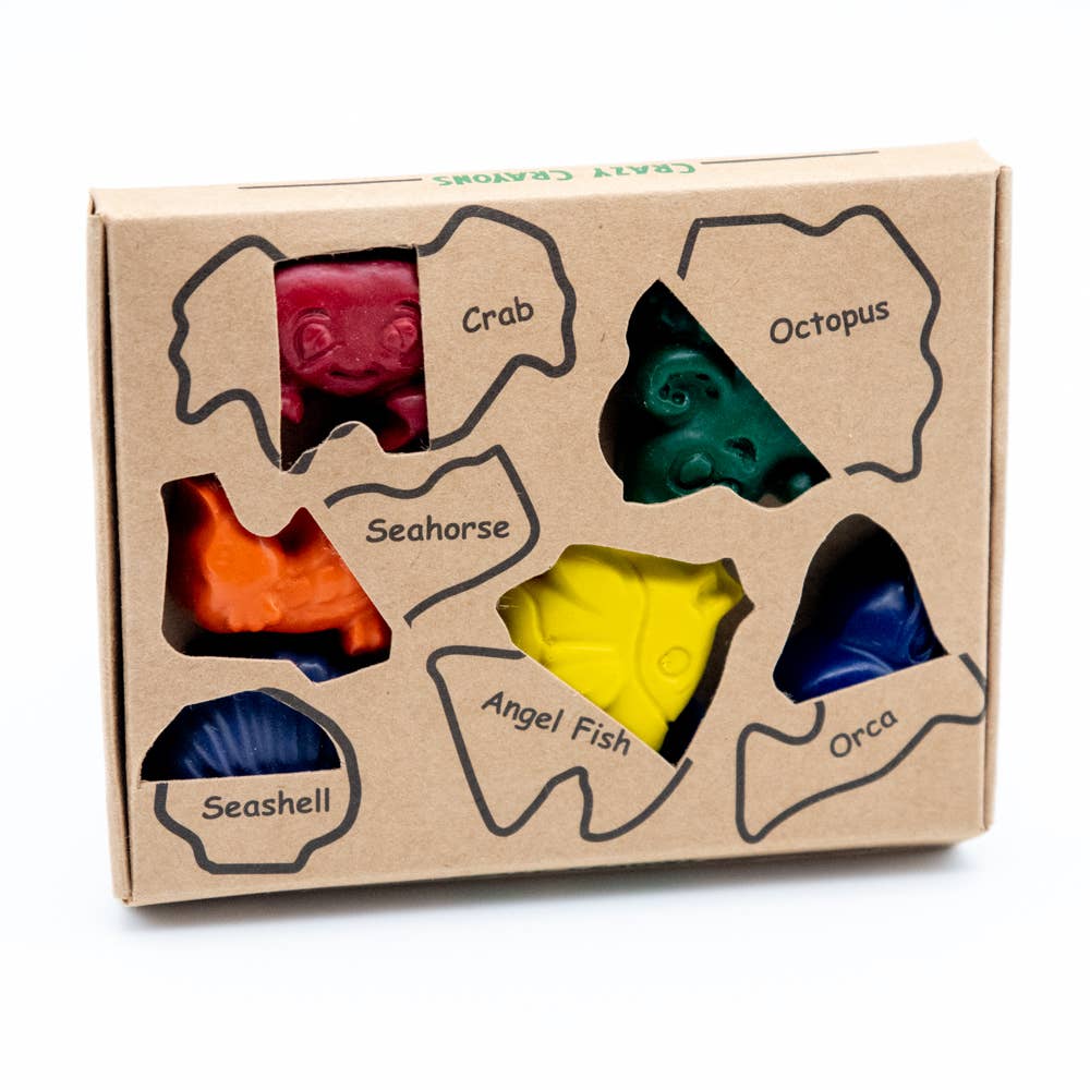 A set of colorful crayons designed to look like ocean animals, including a crab, octopus, seahorse, angel fish, and seashell, packaged in a cardboard box with a clear view of each crayon.
