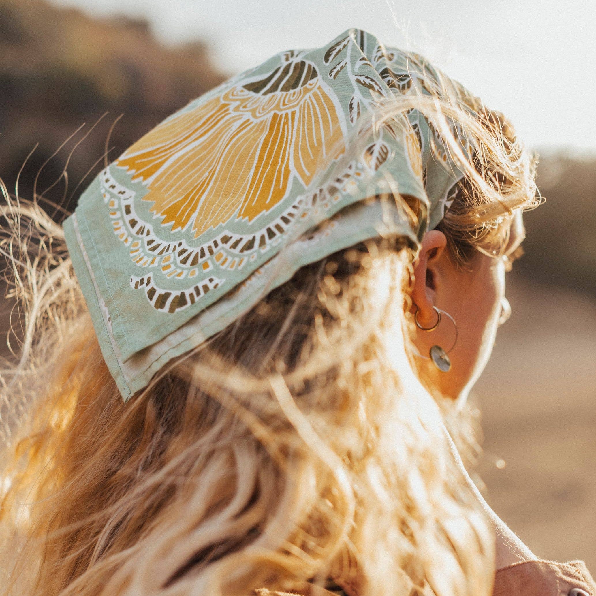Person wearing a cotton bandana on her head with a floral design outdoors