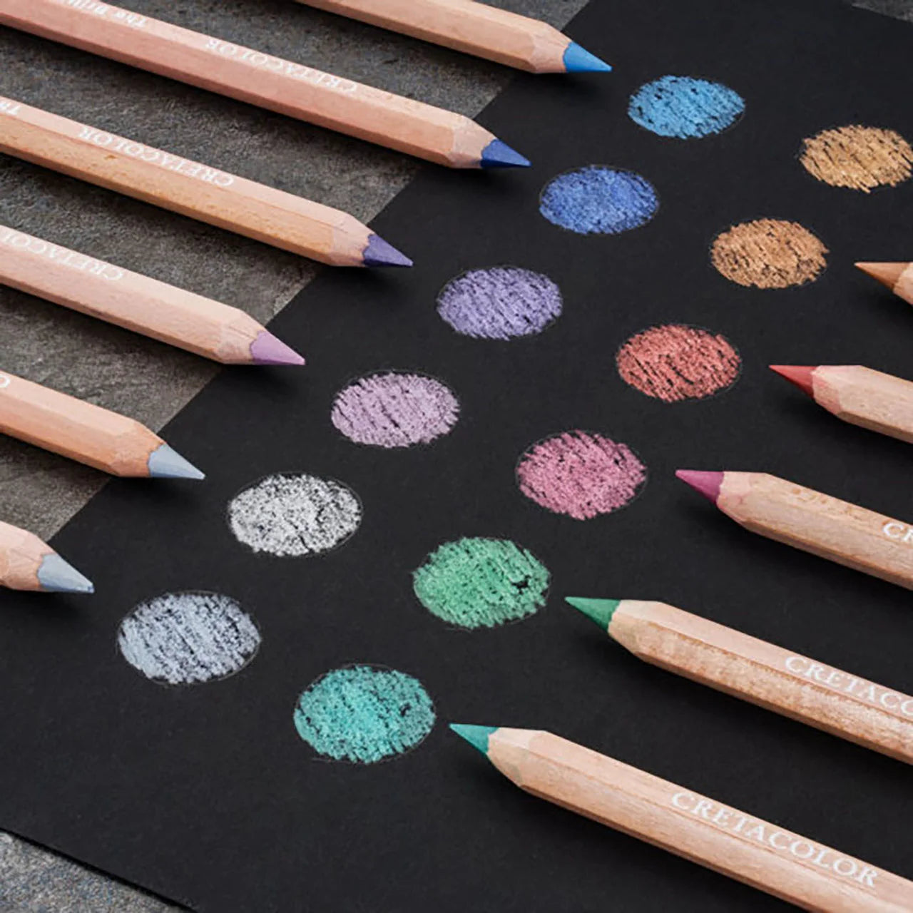 An array of jumbo metallic pencils in various colors, displayed on a surface with their respective color swatches shown on black paper.