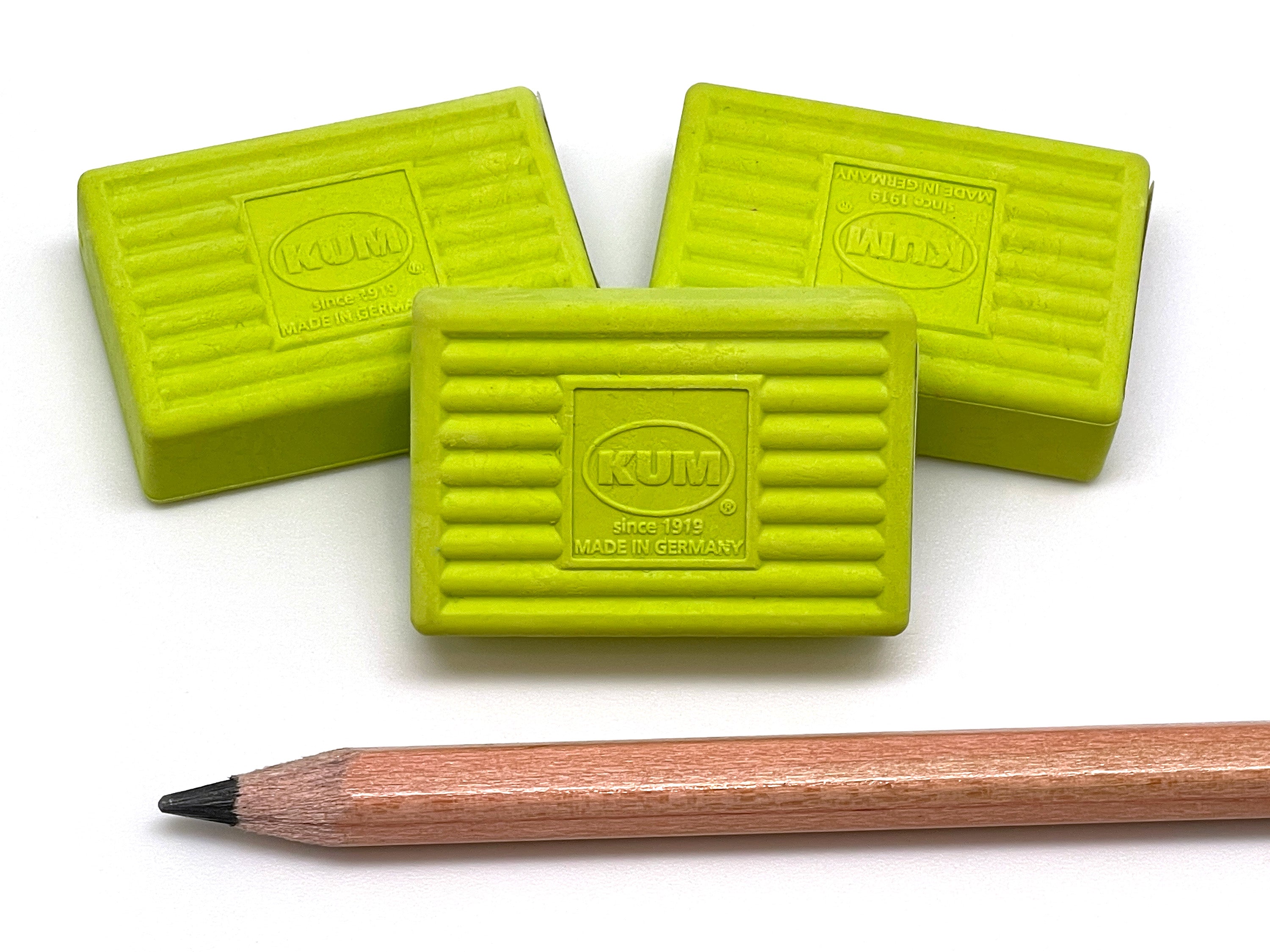 Three green Kum erasers on a white background with a wooden pencil.