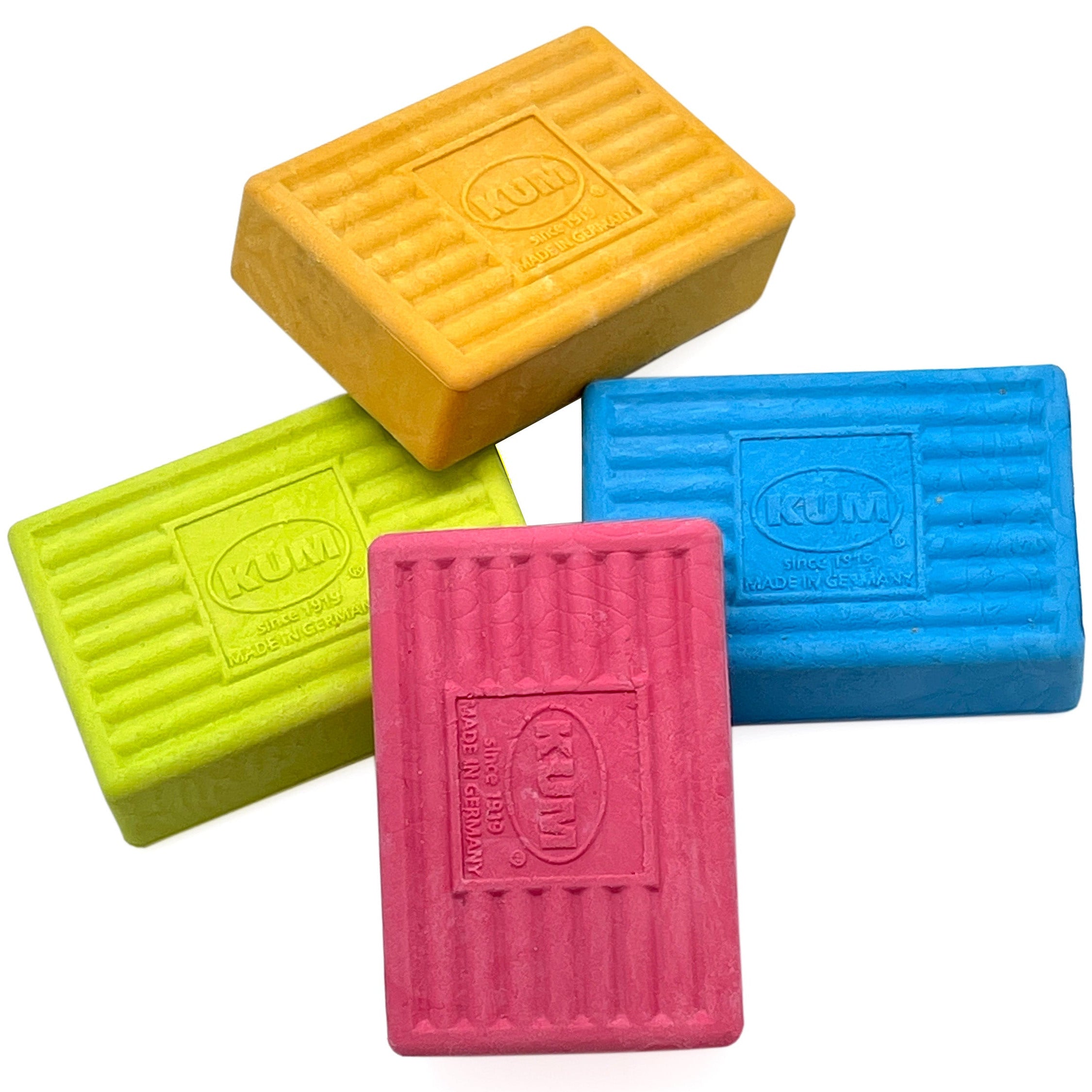 Four colorful rectangular KUM erasers on a white background
