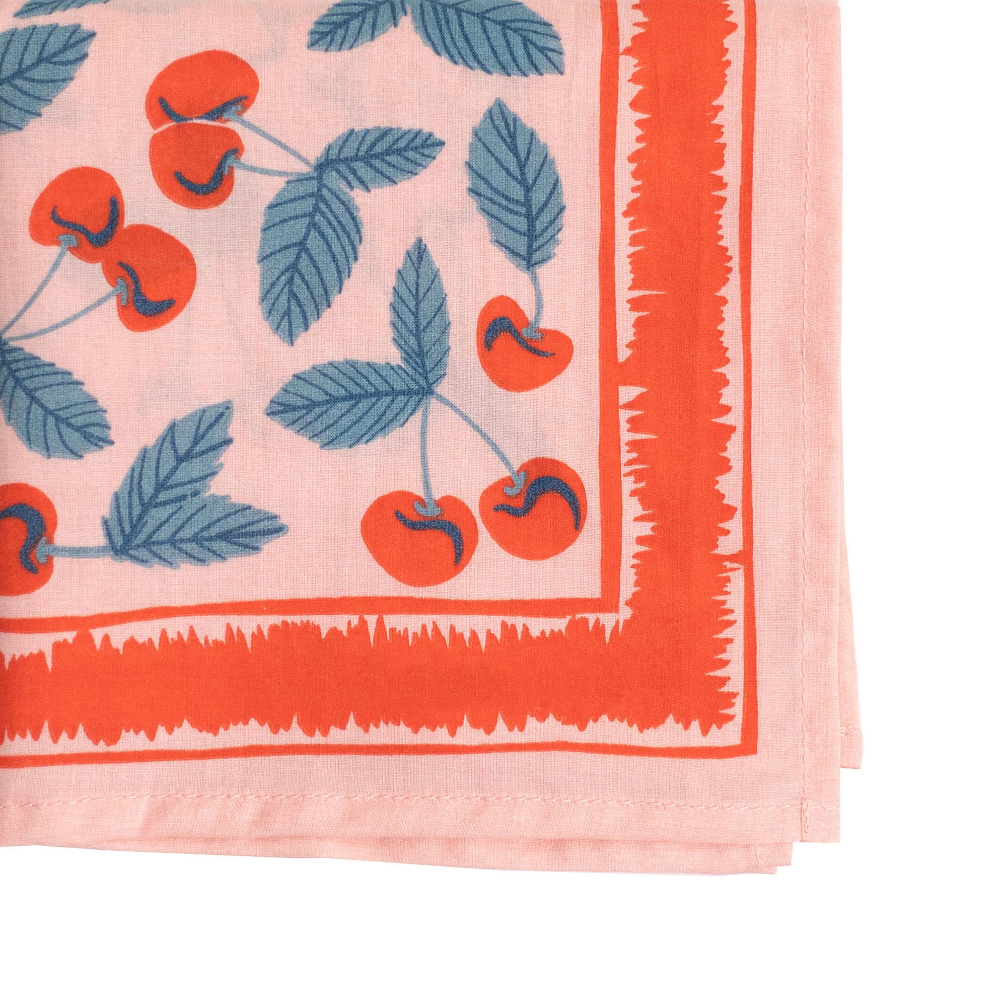 Corner detail photo of bandana with cherry pattern on a pink background