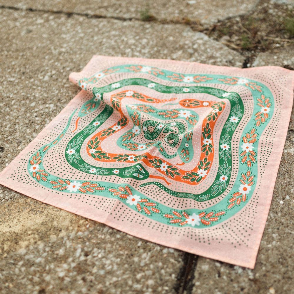 Decorative bandana with green and orange snakes patterns on a concrete surface