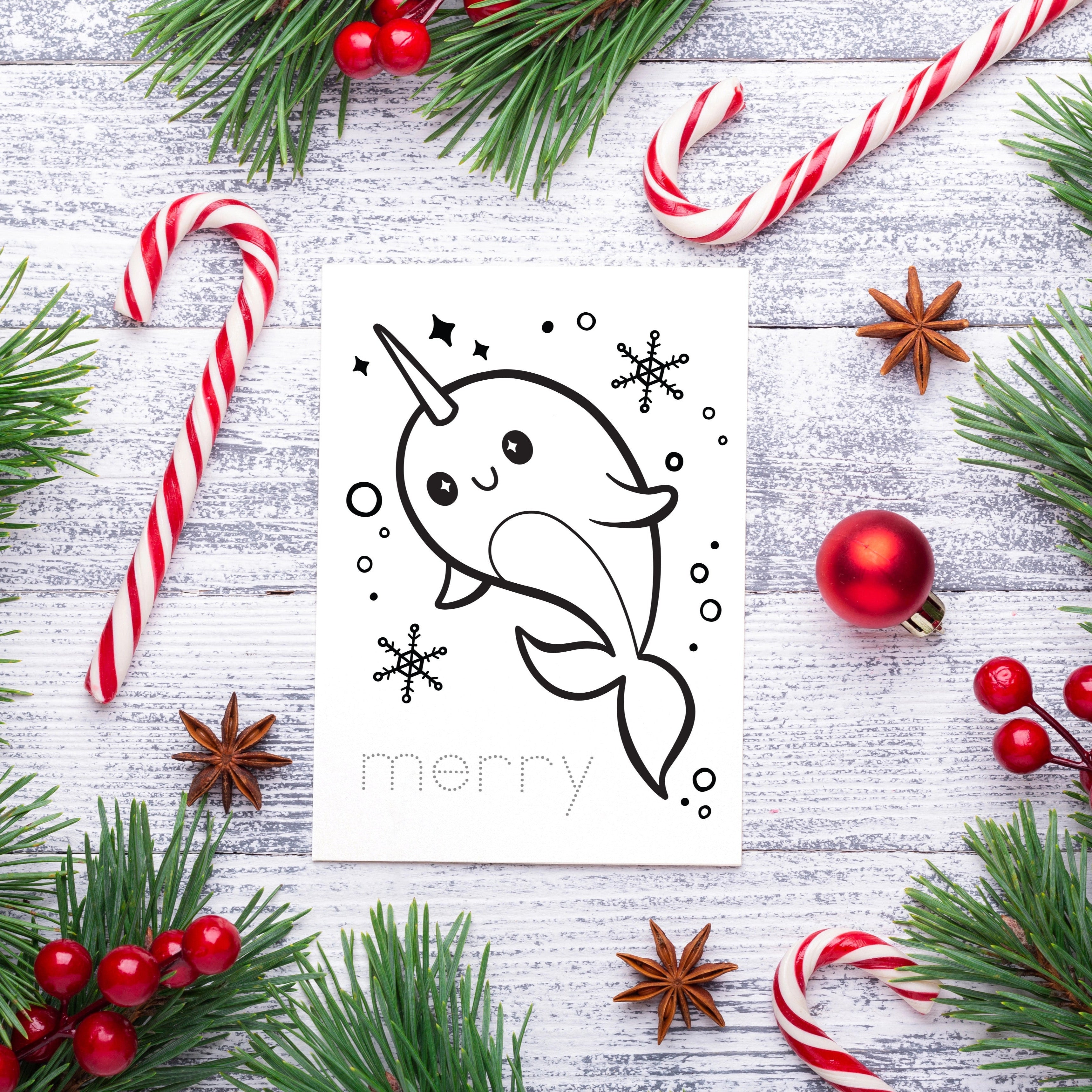Christmas-themed card to color in with a narwhal design, surrounded by candy canes, pine branches, and berries on a light wooden background.
