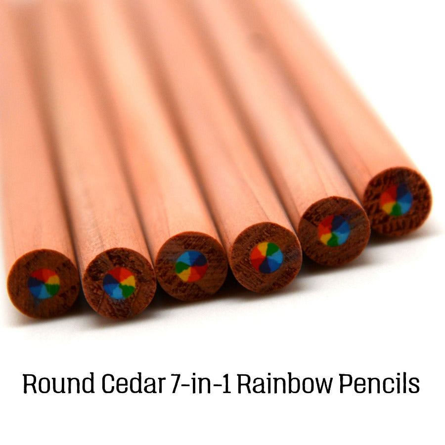 Six round cedar pencils fanned out on a white background, showing their natural cedar wood ends with multi-color rainbow core. Text at the bottom reads 'Round Cedar 7-in-1 Rainbow Pencils'.