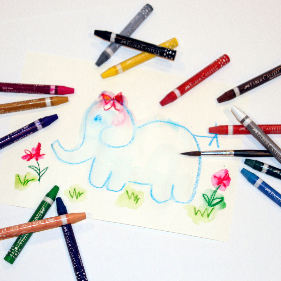 A selection of triangular watercolor crayons in various colors laid out next to a drawing of a blue elephant and some flowers. The crayons have a triangular cross-section and are labeled with brand names.