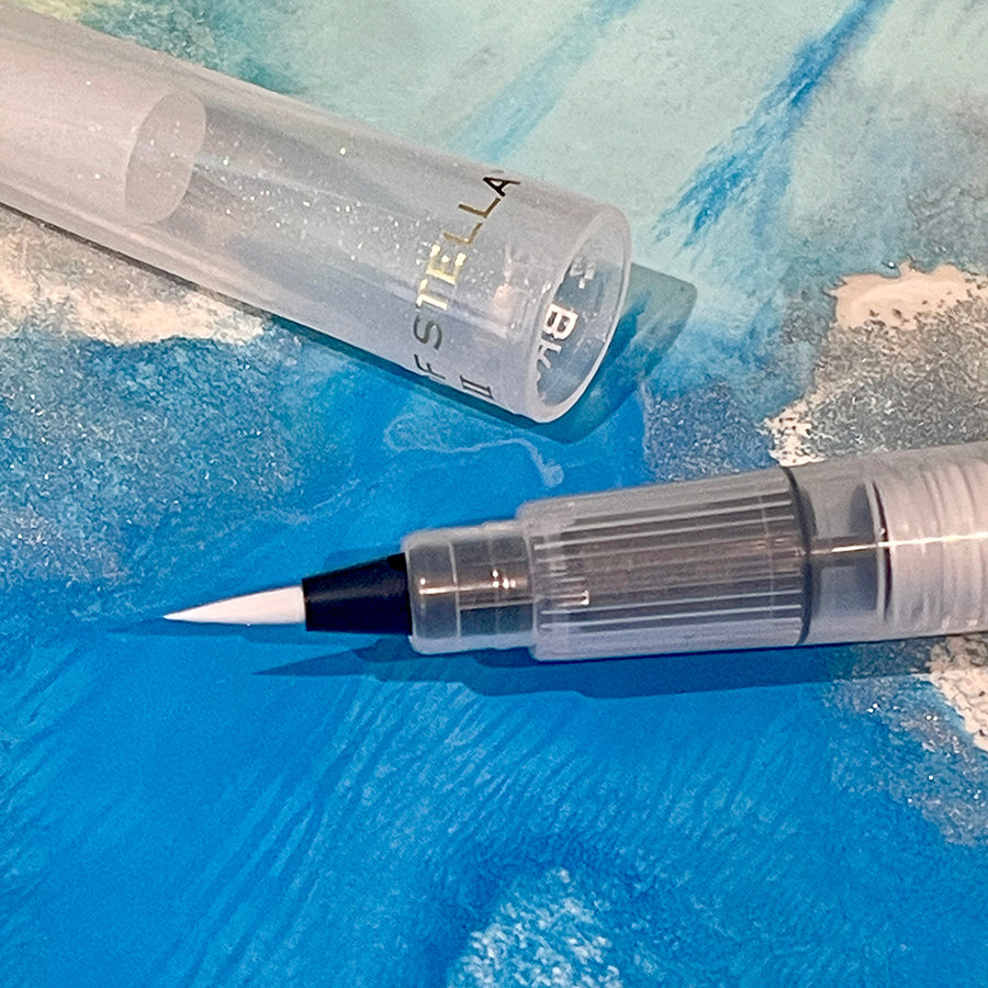 Glitter shimmer brush tip pen with clear ink on a blue background