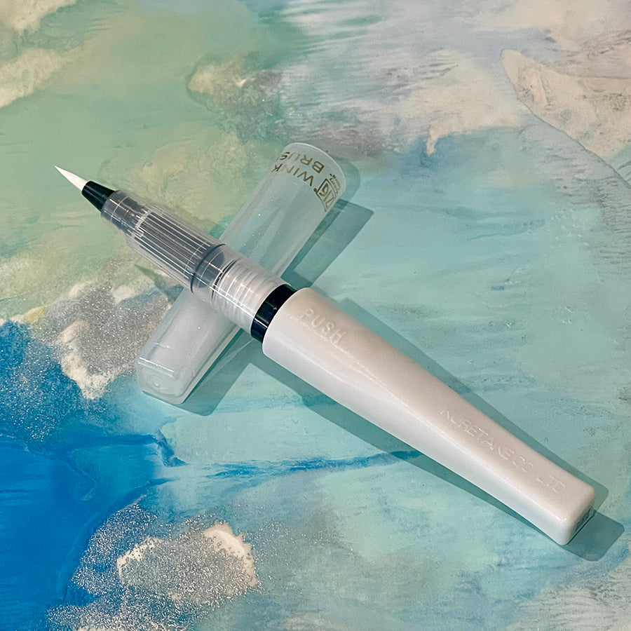 Glitter brush tip pen on a pastel blue background