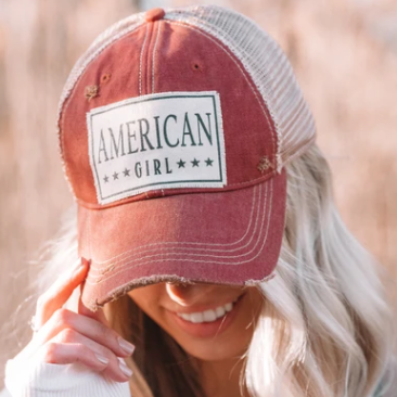 Person wearing a 'American Girl' cap with a blurred background