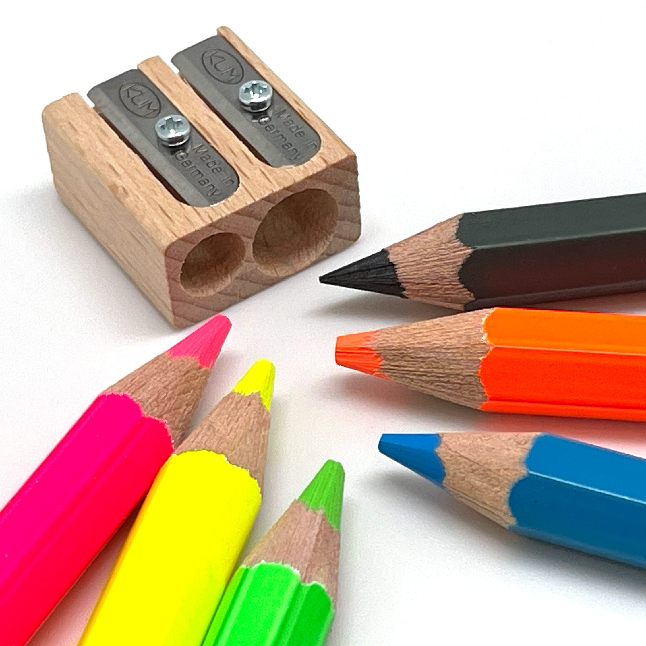 Colorful pencils and a wooden sharpener on a white background