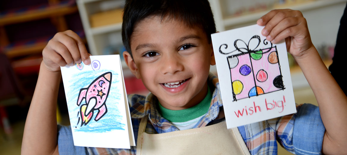 Smiling child holding two handmade, colored greeting cards — featuring bold, easy-to-color designs from Stubby Pencil Studio.