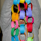 Child holding a long colorful paper chain with various colors.