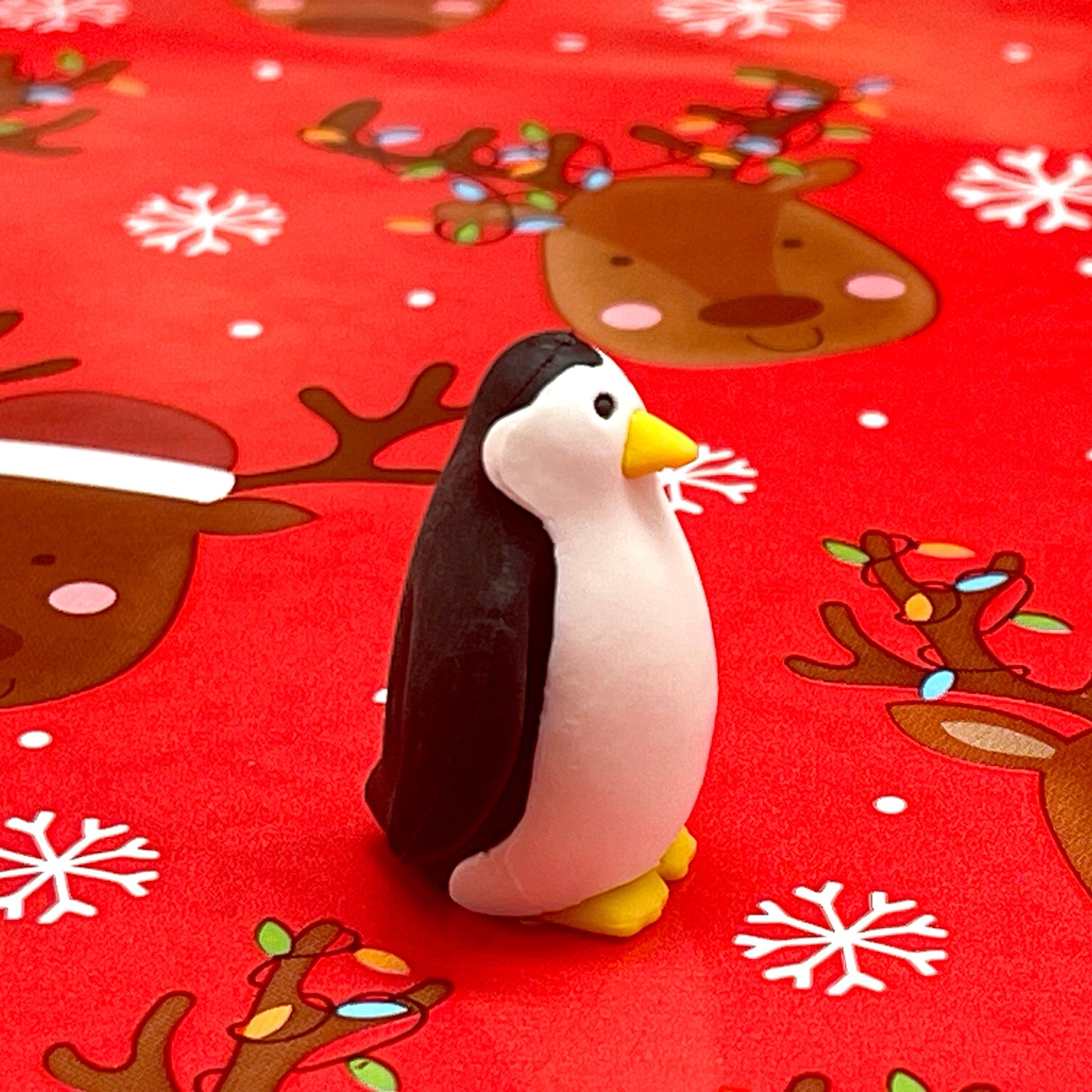 Penguin eraser on a red background with reindeer and snowflake pattern