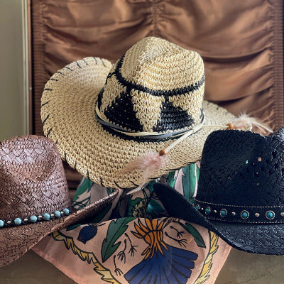 Display of western hats made of woven straw with a pink cotton wild rag bandana scarf