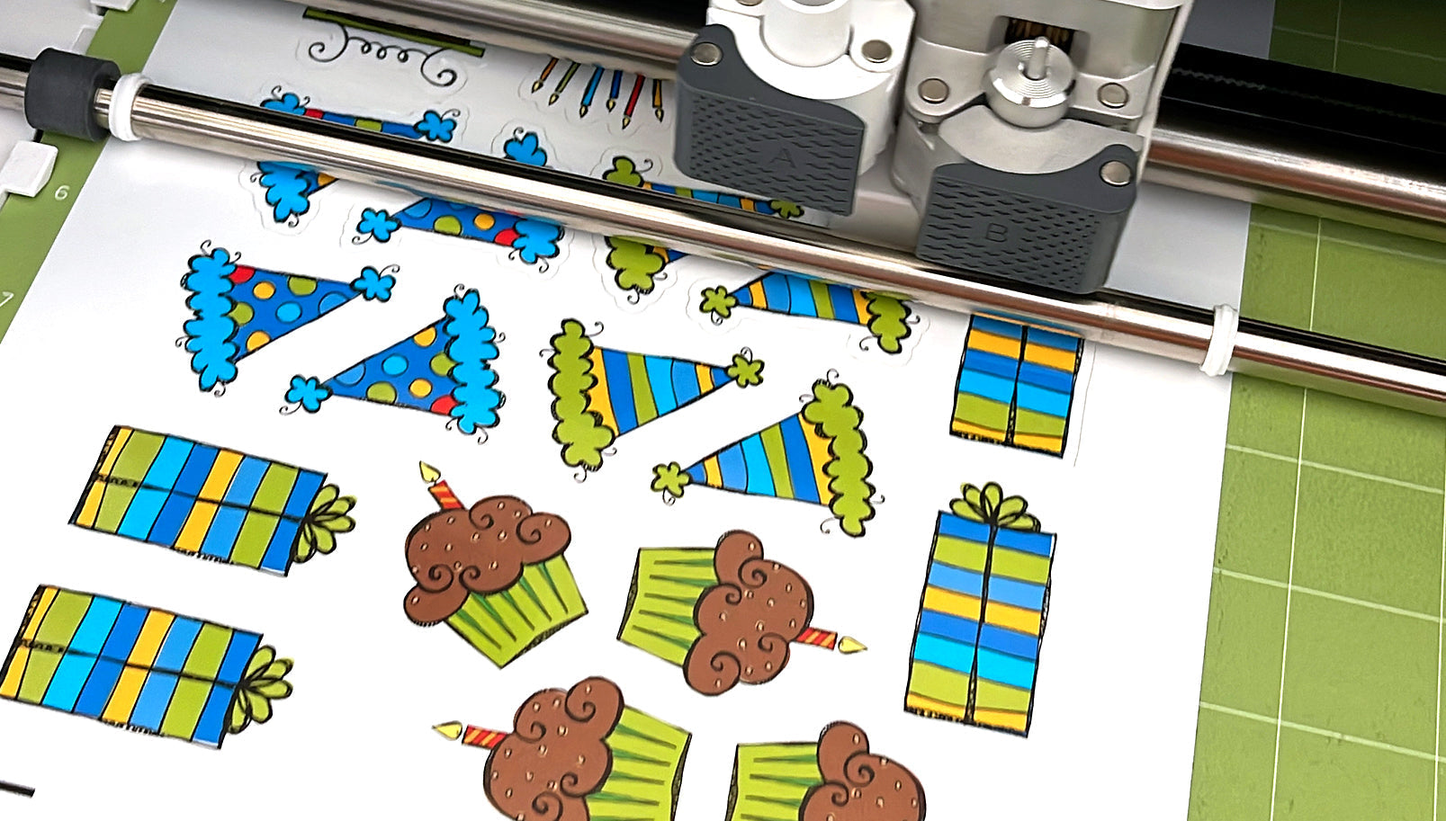 Birthday sticker sheet with party hats, presents, and cupcakes being cut on a Cricut machine