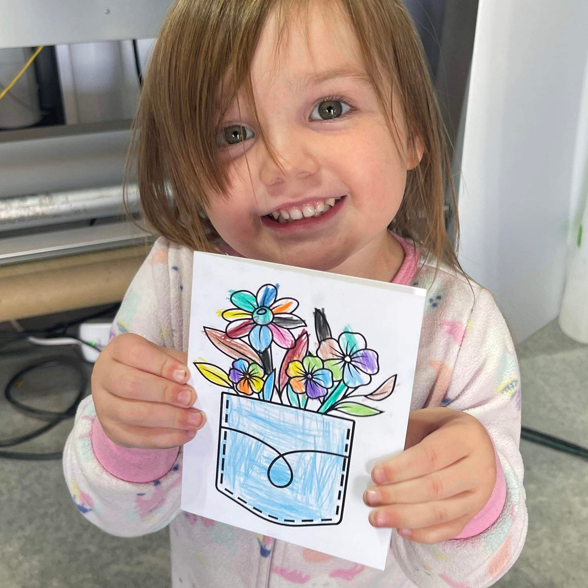Little girl holding a bold and easy coloring card she made of flowers in a pocket