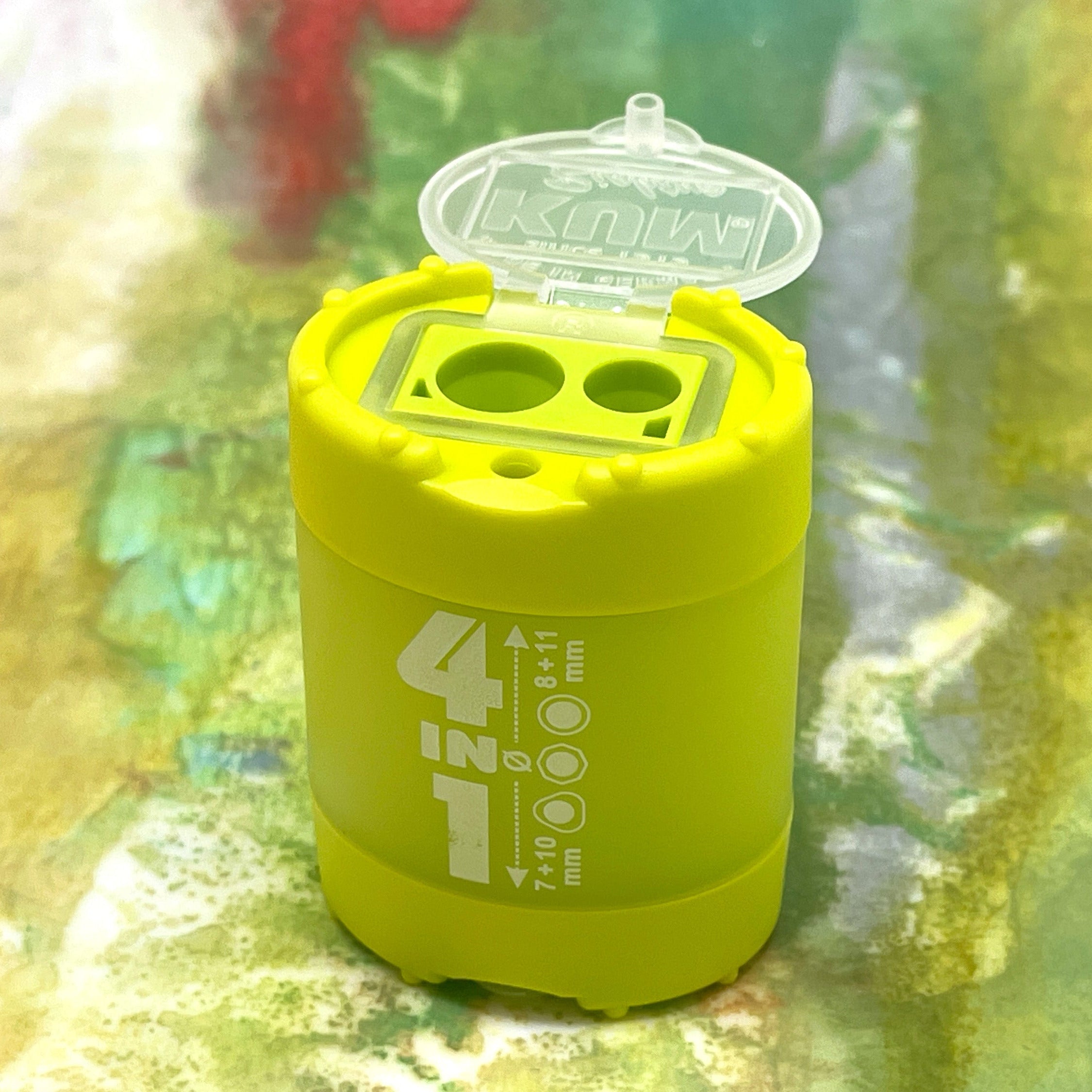 Lime green pencil sharpener with a clear lid on a colorful, blurred background