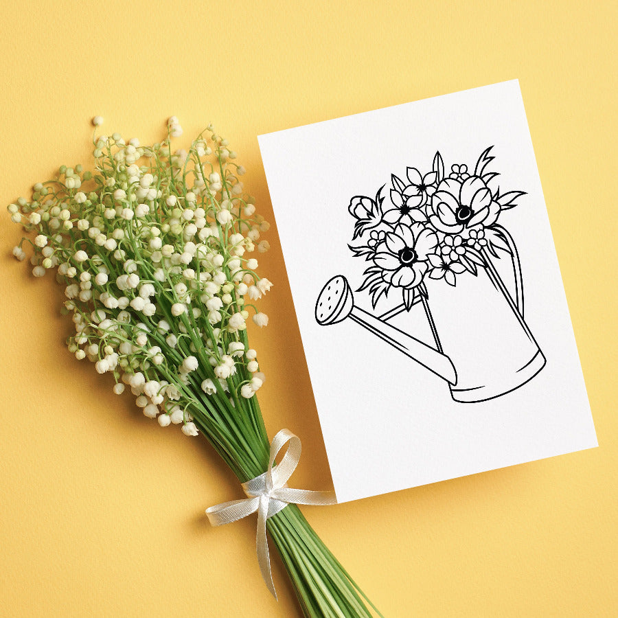 A greeting card with illustration of a watering can to color in and personalize laying on a yellow background next to bouquet of flowers