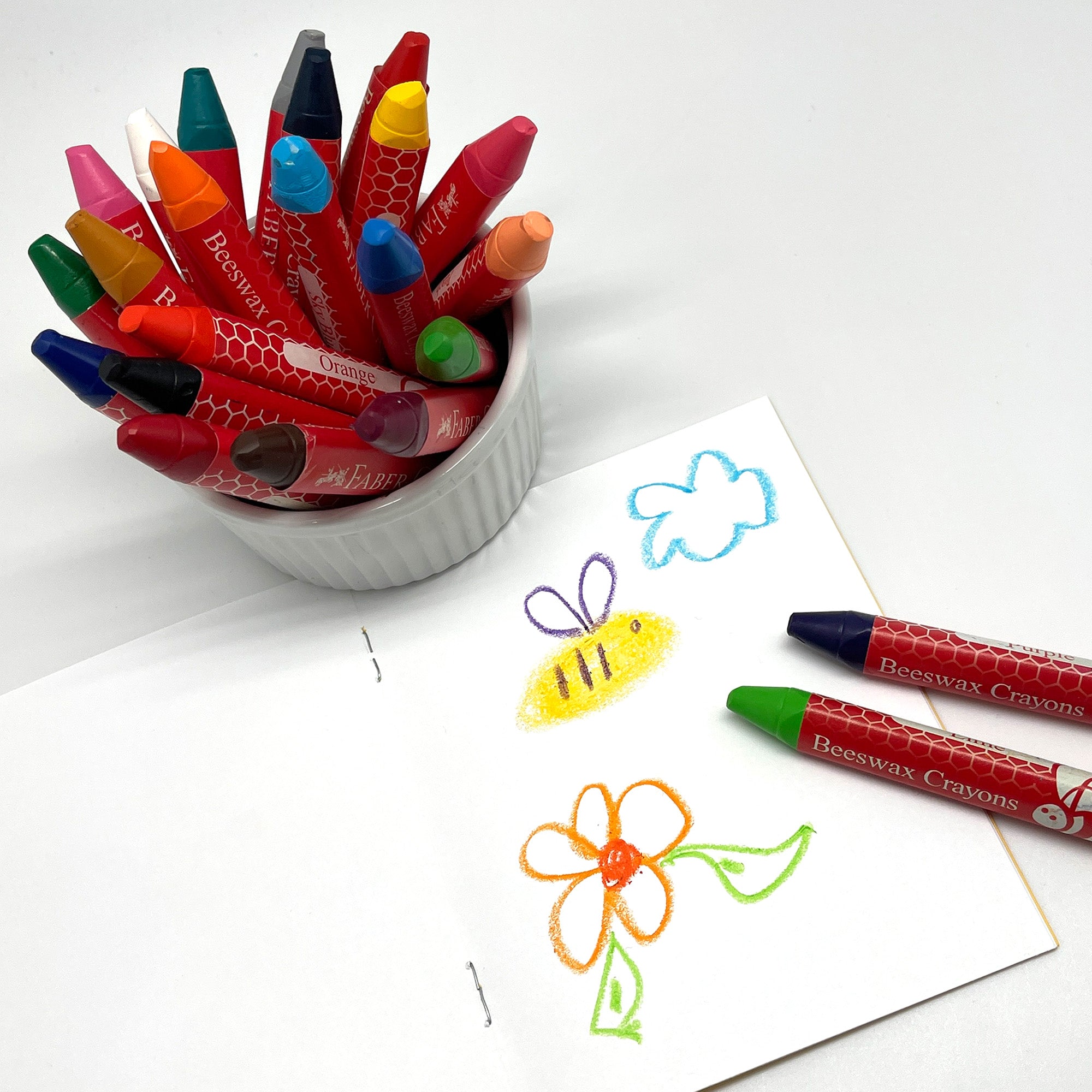Beeswax Crayons in a white container next to a drawing of a bee and flower. Triangular Jumbo Beeswax Crayons Easy Grip for Children