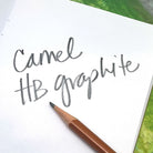 Notebook with 'Camel HB graphite' text and a pencil on a green surface