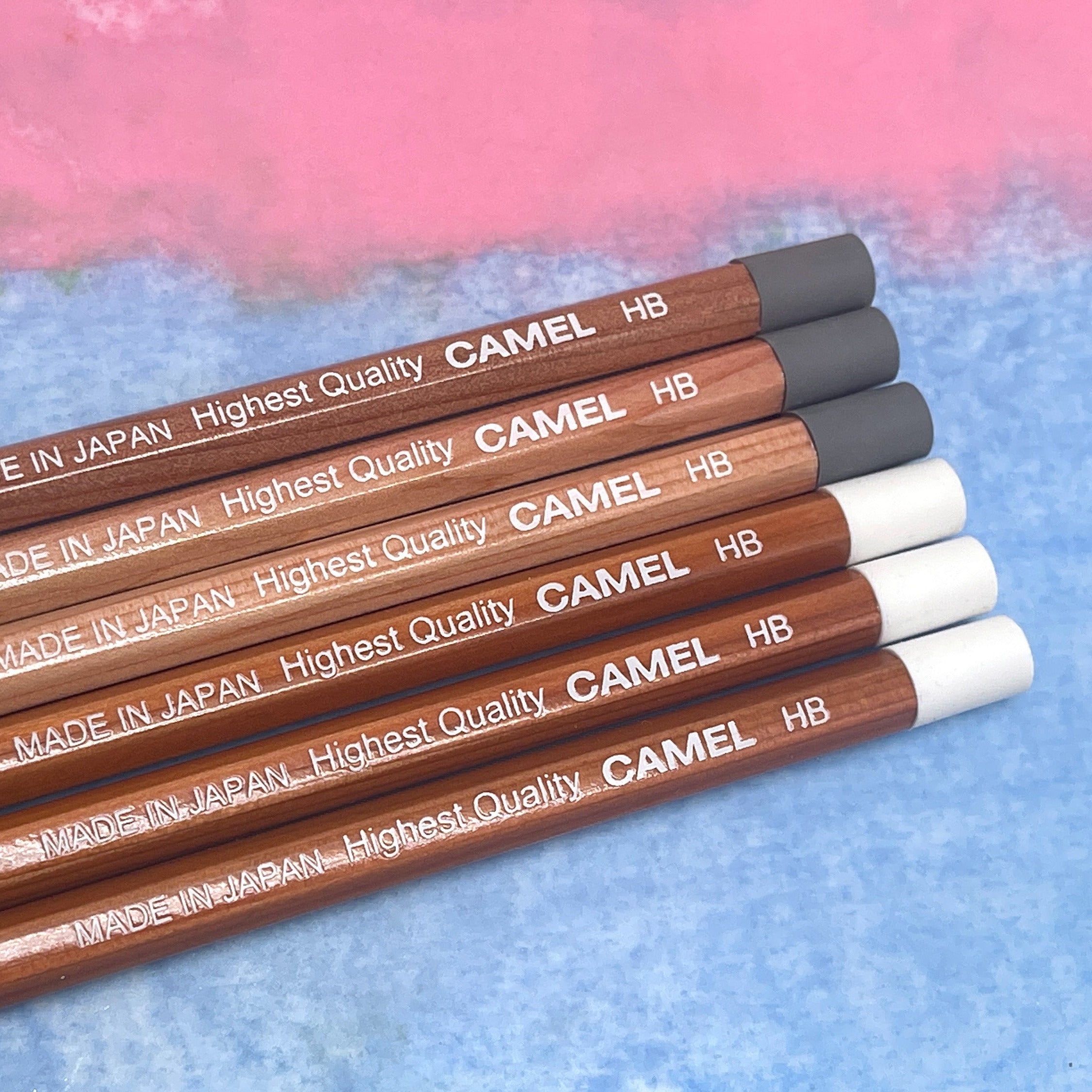 Camel pencils with 'Made in Japan' text on a blue and pink gradient background