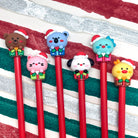 Set of Christmas gel pens with Kawaii style animals wearing Santa hats on a striped background