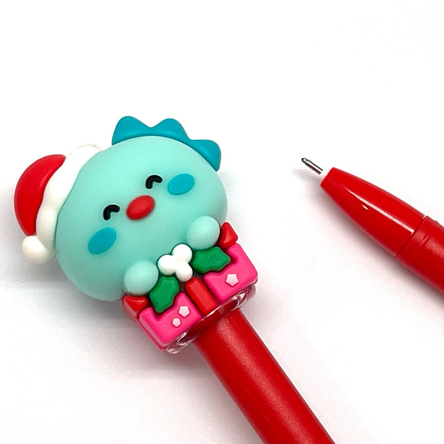 Red gel pen with a turquoise dinosaur head wearing a Santa hat pen cap on a white background