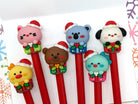 Set of six gel pens with Kawaii style animals wearing Christmas hats and sitting on gift boxes on the pen lid.