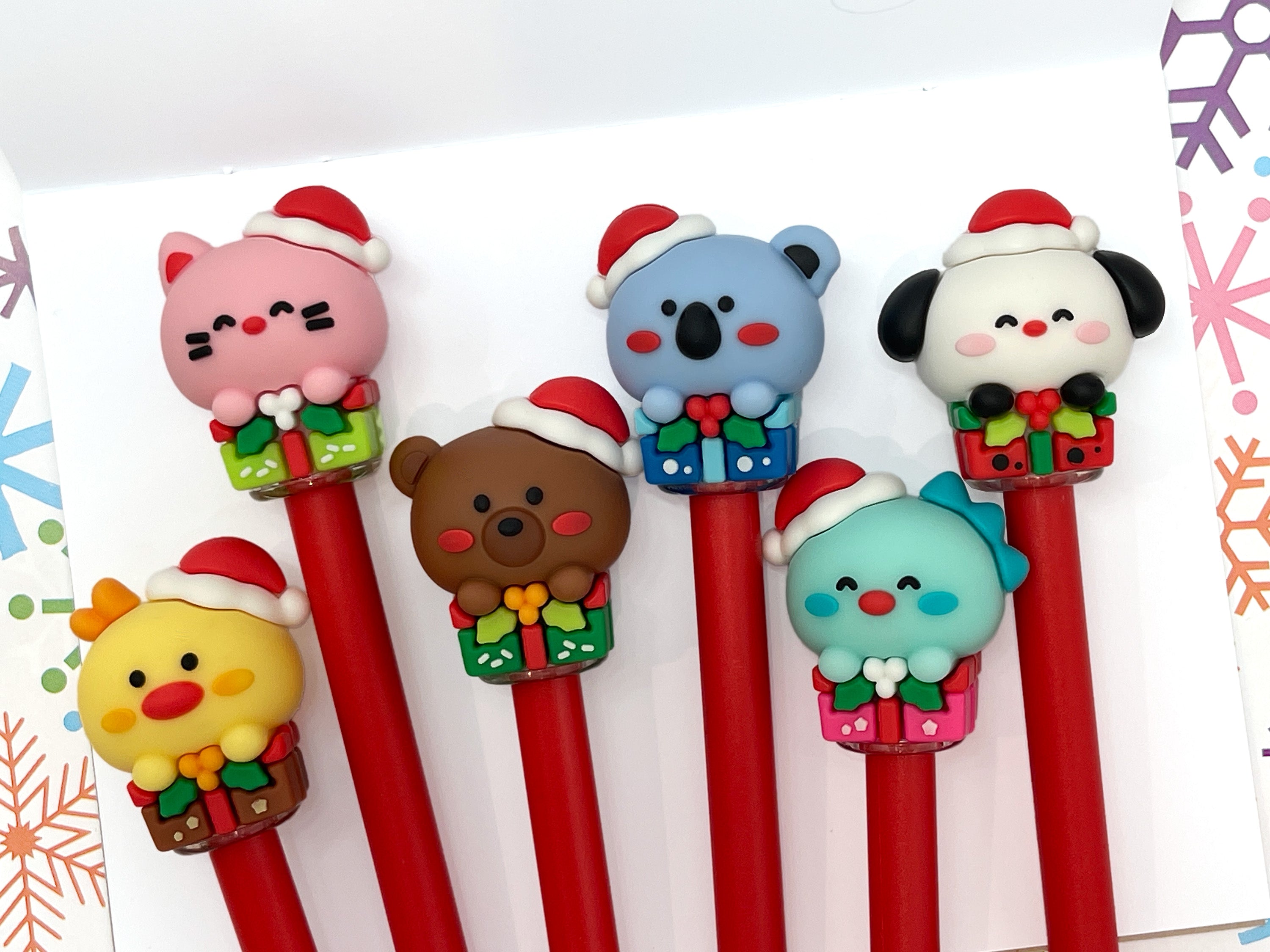 Set of six gel pens with Kawaii style animals wearing Christmas hats and sitting on gift boxes on the pen lid.