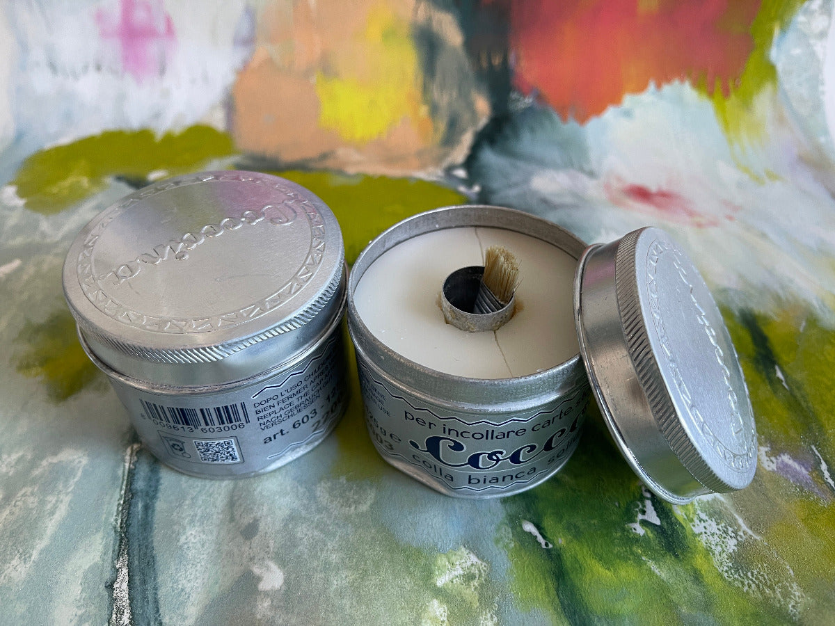Two tins of paste that are slightly dented and cracked against a colorful background