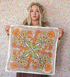 Woman holding a floral patterned cotton scarf against a floral wallpaper background