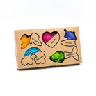 A variety of colorful crayons in different shapes including a heart, a fish, a rainbow, and a mermaid tail, displayed in an eco-friendly packaging.