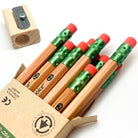 Set of incense-cedar wooden pencils with red erasers in an open box, and pencil sharpener on a white background.