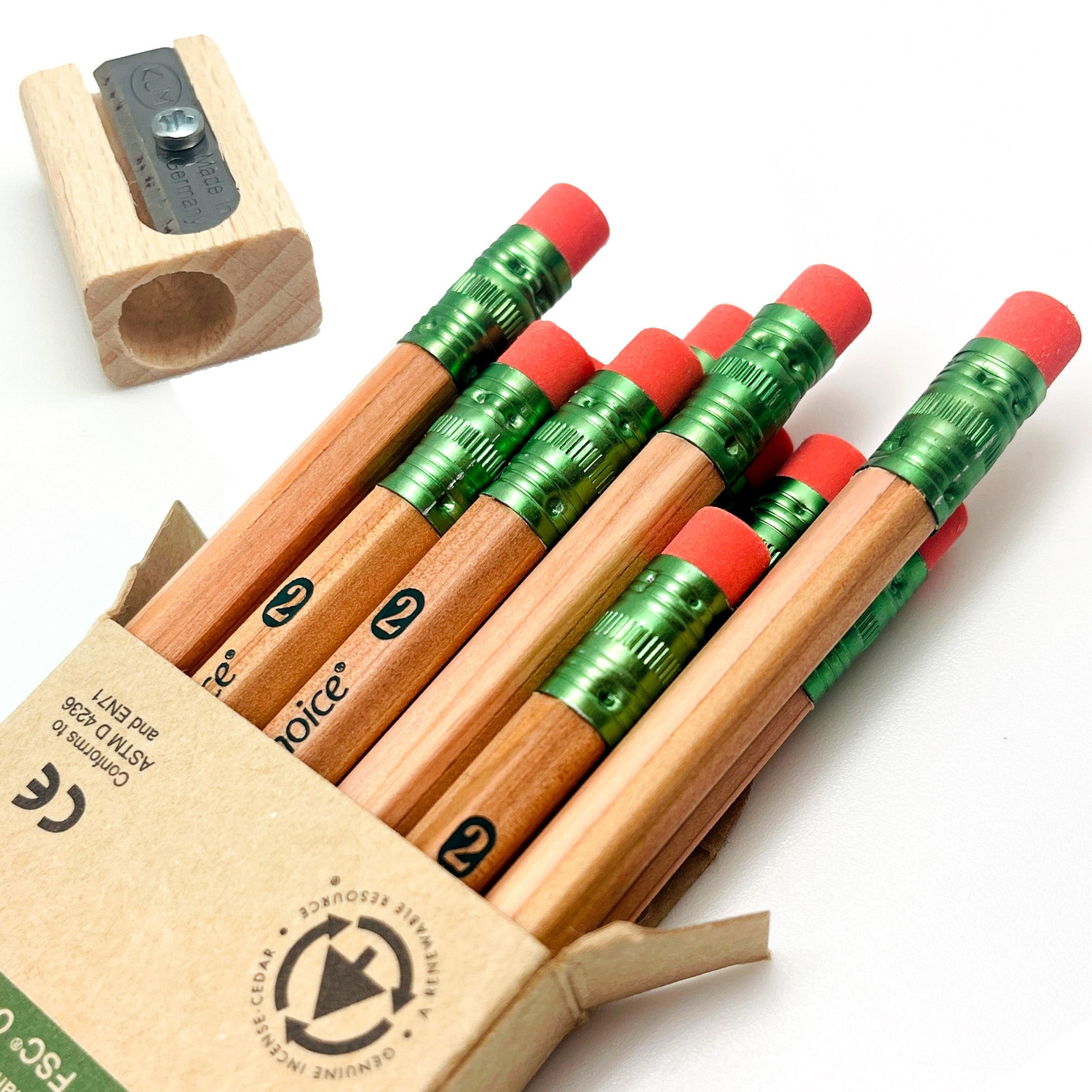 Set of incense-cedar wooden pencils with red erasers in an open box, and pencil sharpener on a white background.