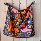 Colorful cotton bandana scarf draped over a wooden surface. Folk art chickens and birds pattern.