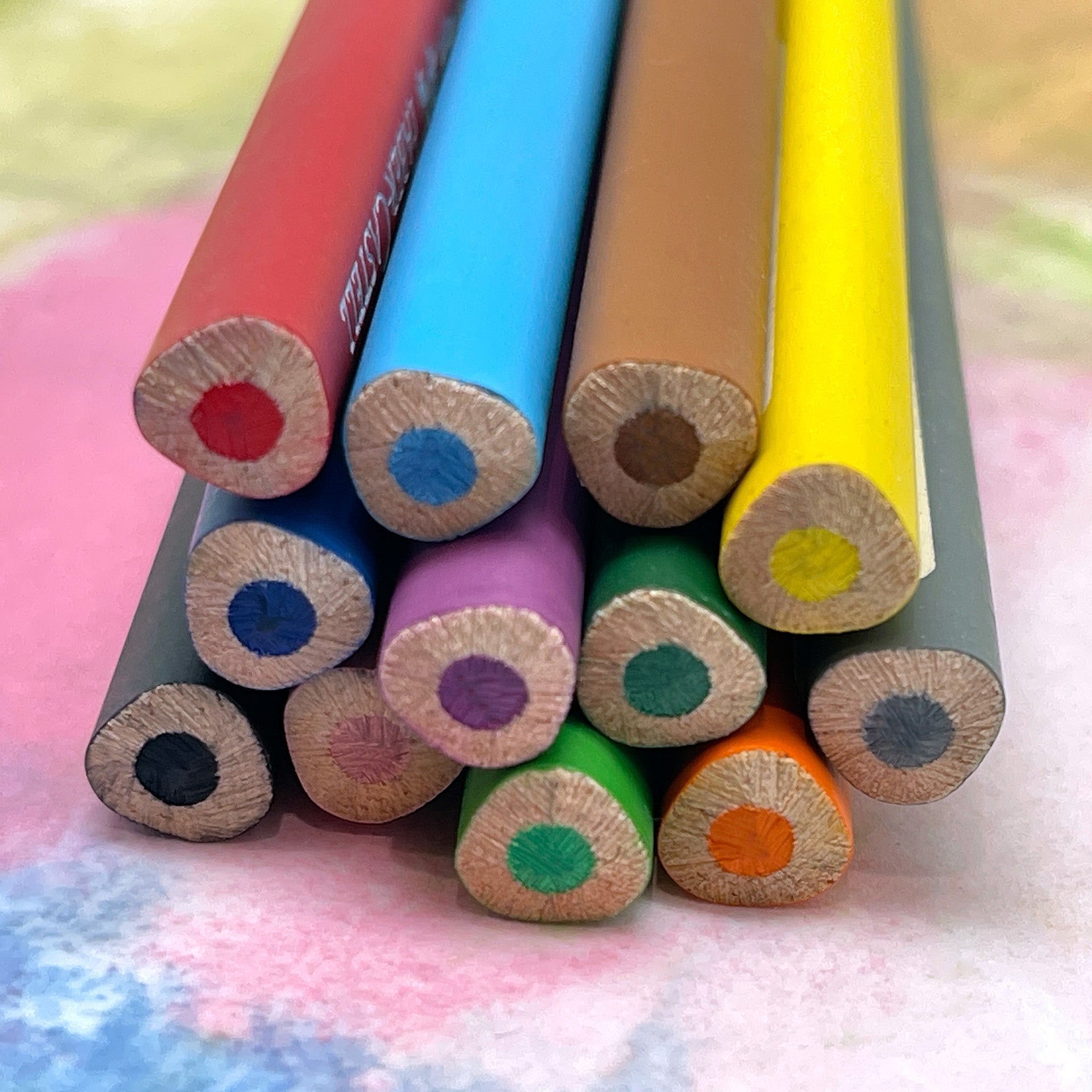 Colorful watercolor pencils with triangular shape ends on a textured surface