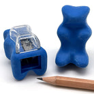 2 blue gummy bear-shaped erasers with built in pencil sharpener next to a wooden pencil on a white background