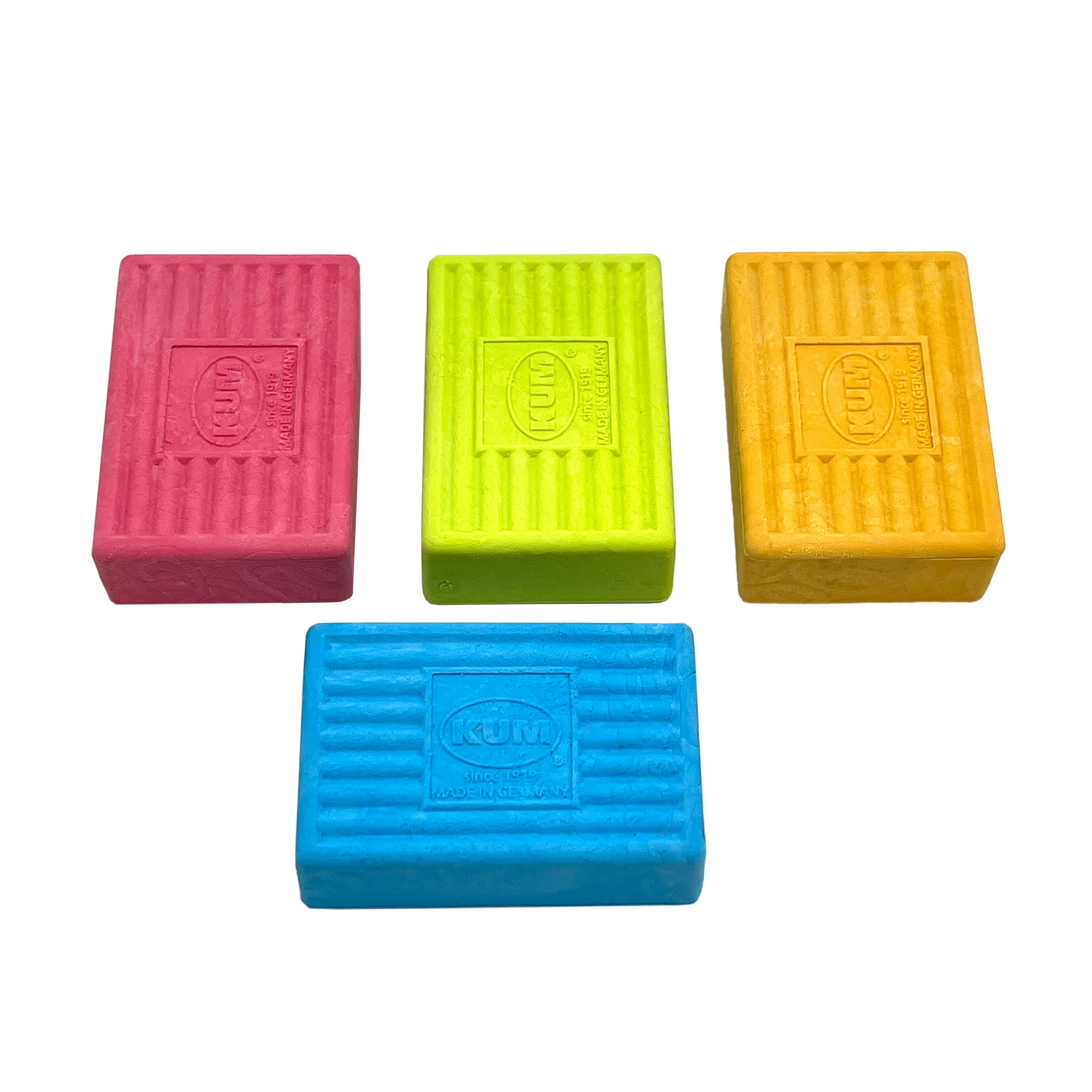 A set of KUM brick-shaped erasers in pink, green, yellow, and blue colors on a white background.