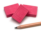 Three pink KUM erasers with a pencil on a white background