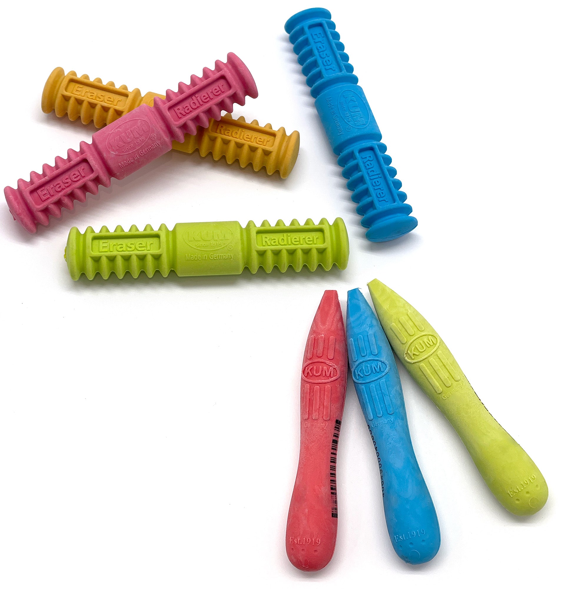 A collection of colorful stick-shaped erasers with grip zone lines, made by KUM in Germany.