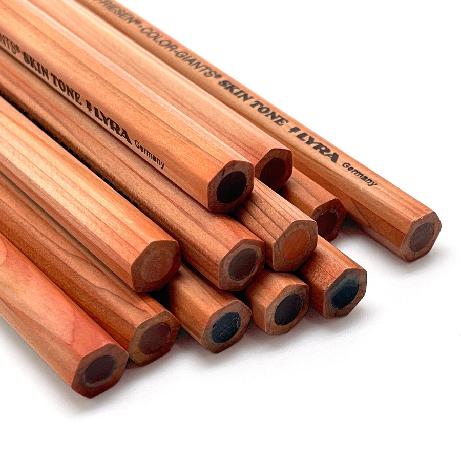 A close-up studio shot of several wooden drawing pencils arranged diagonally on a white background. The pencils are light brown wood with black printed text on the barrels, including the brand Lyra