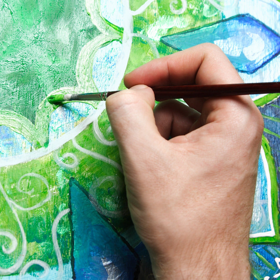 Human hand holding a paint brush with original art painting background