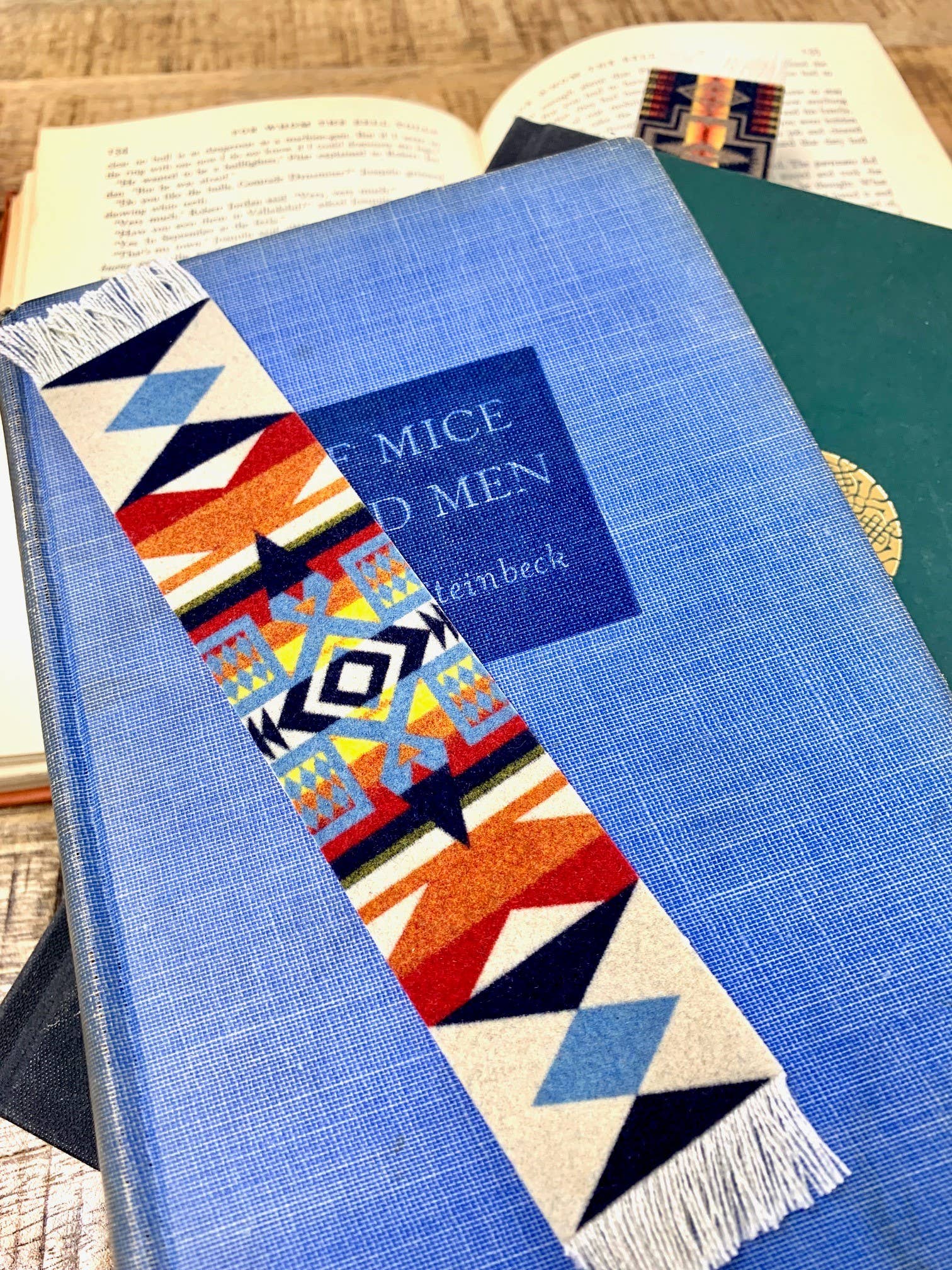 Colorful geometric Pendleton blanket pattern bookmark on a blue book with 'Of Mice and Men' visible