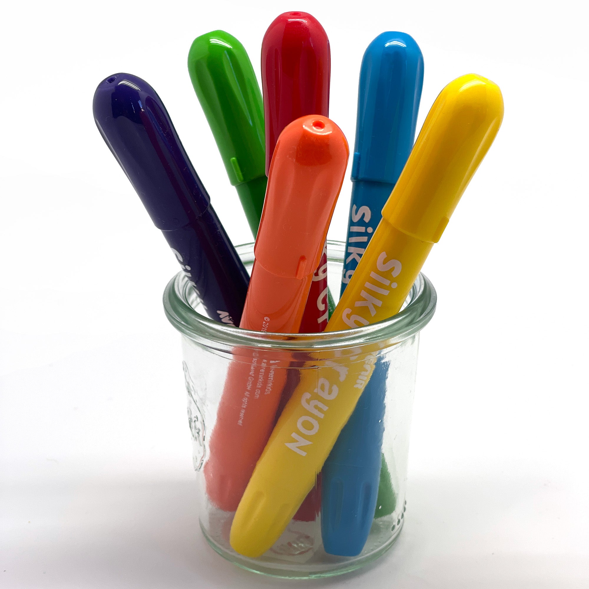 Silky watercolor crayons in a glass jar on a white background