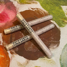 Three Palo Santo scented soaking bath salt tubes on a colorful fabric background