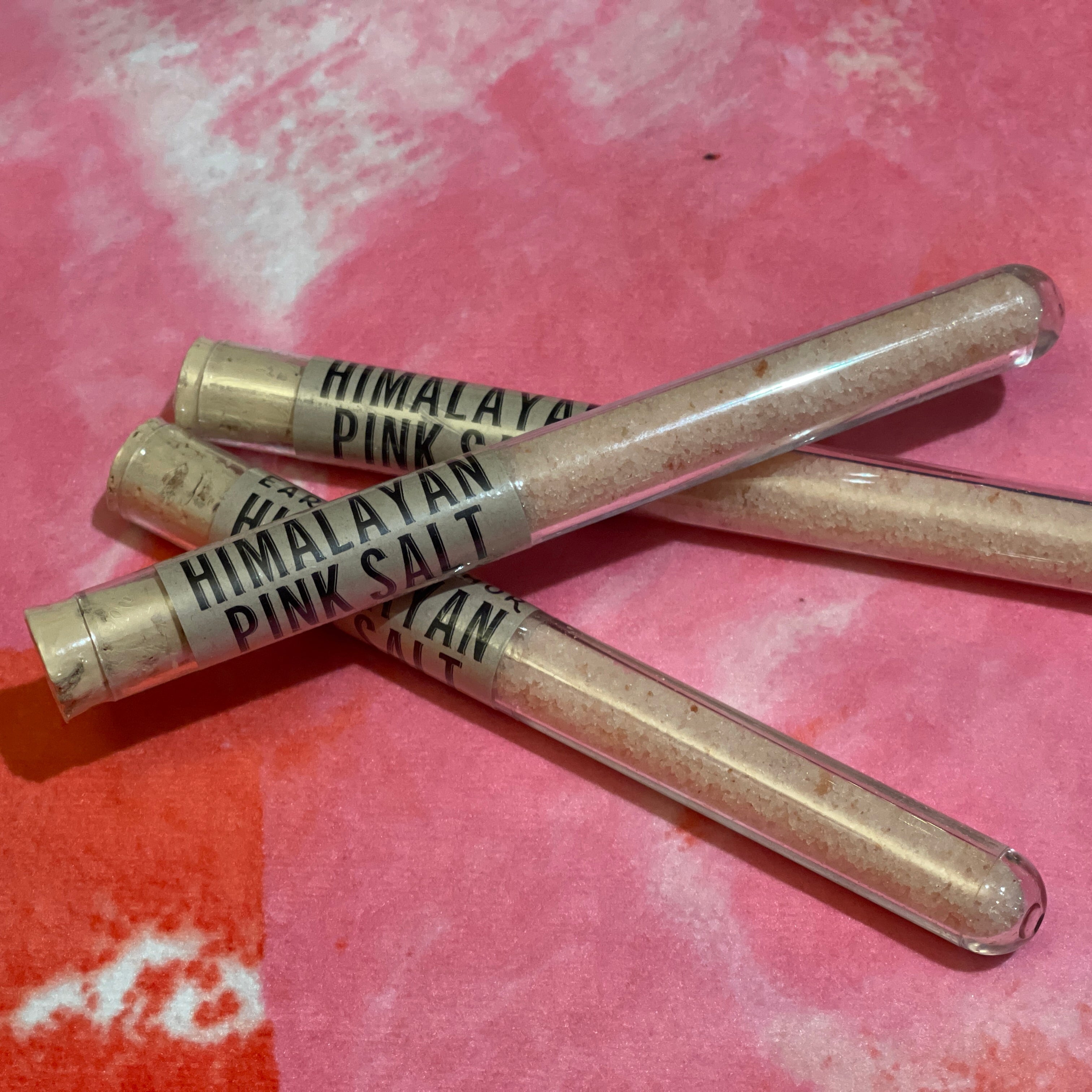 Himalayan pink bath salt tubes on a pink and white textured background