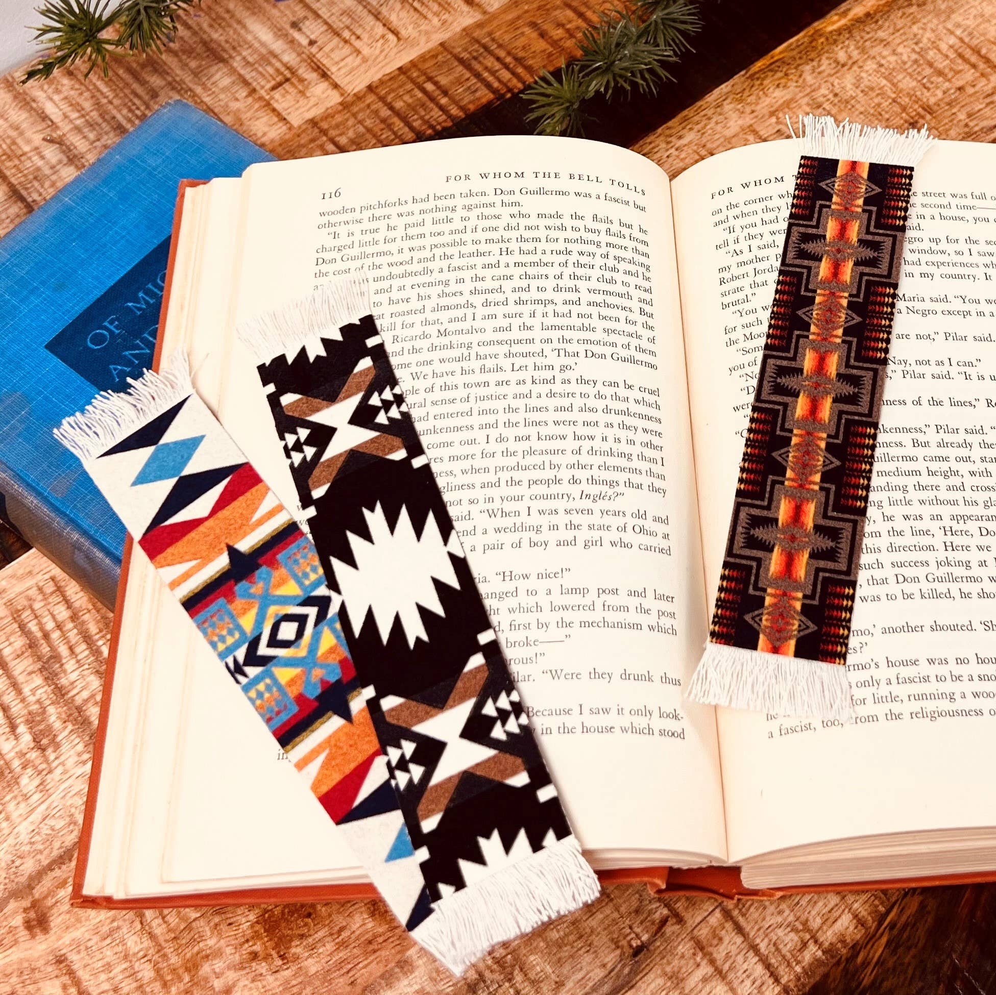 Open book with three colorful Pendleton Blanket patterned bookmarks on a wooden surface