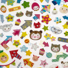 A variety of colorful stickers including animal faces, geometric shapes, and other adorable designs spread out on a surface.